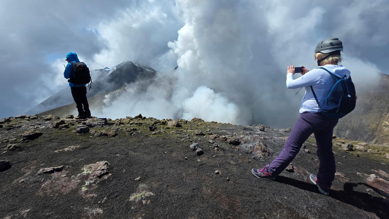Visitors on the crater rim as steam clouds rise from Etna's summit
